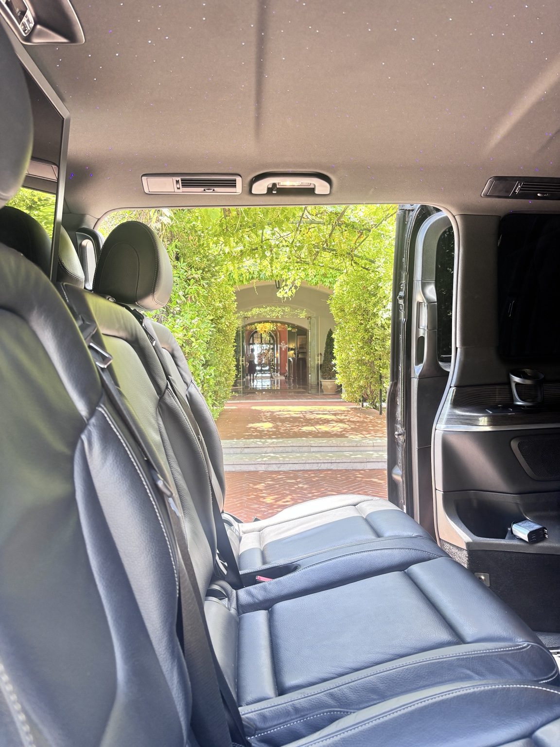 Intérieur Mercedes Classe V — ciel étoilé et porte ouverte sur un palace de la Riviera